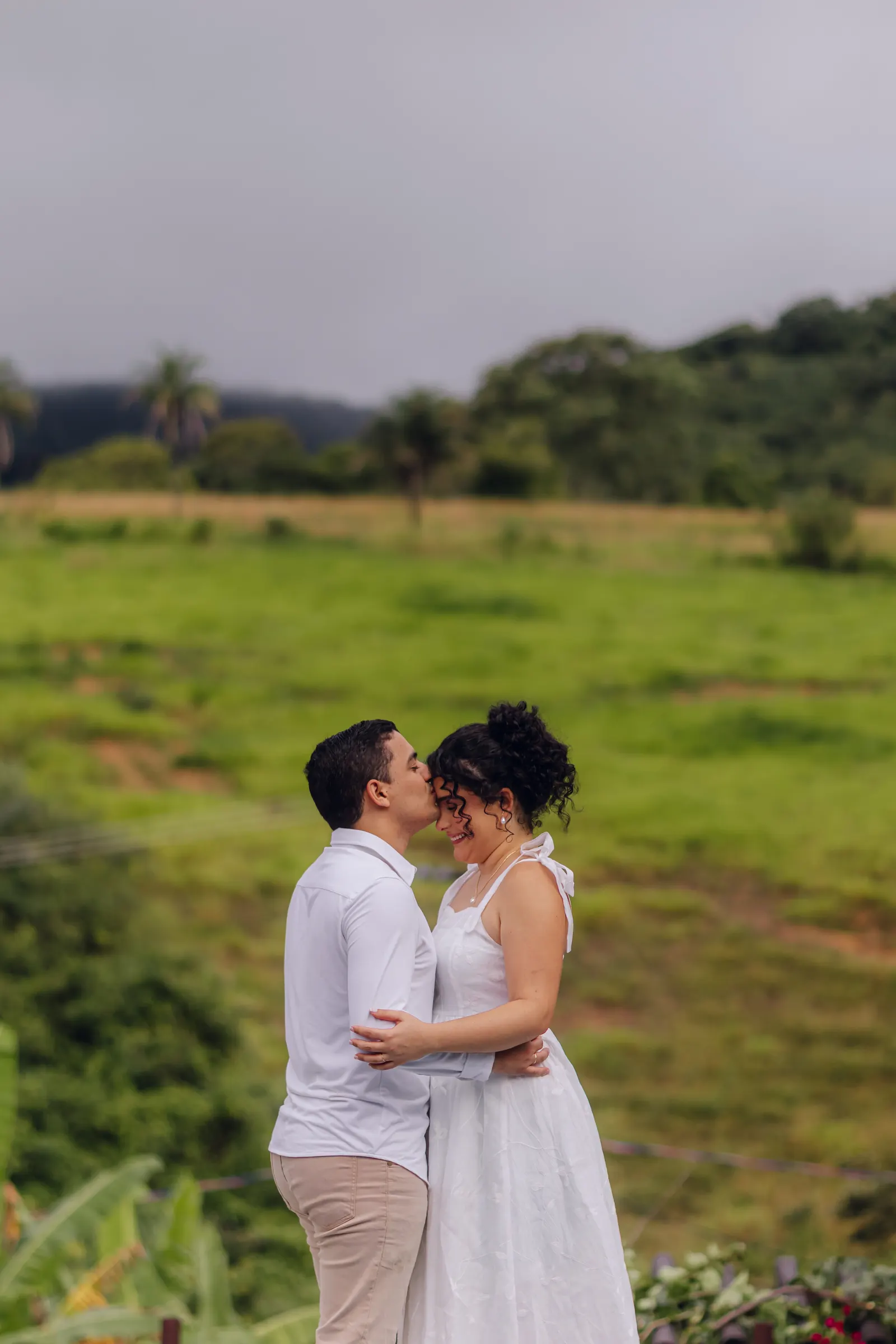 Paula e André se abraçando em um campo verde